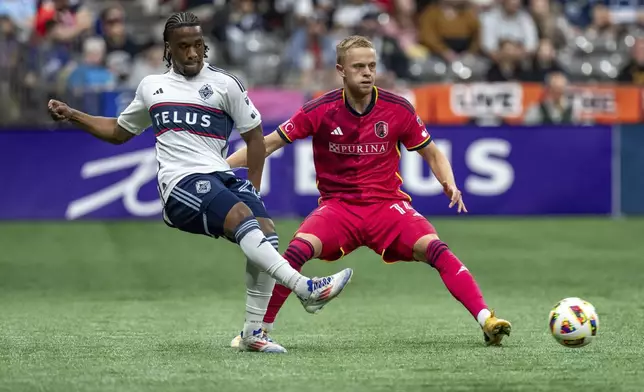 Vancouver Whitecaps' Levonte Johnson kicks the ball past St. Louis City's Tomas Totland (14) during the first half of an MLS soccer match Saturday, June 29, 2024, in Vancouver, British Columbia. (Ethan Cairns/The Canadian Press via AP)