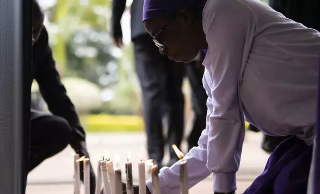 A mourner lights a candle in Lilongwe, Malawi, Wednesday, June 12, 2024, following the death of Malawi's Vice President, Saulos Chilima, in a plane crash Monday. The Malawi government says that Chilima will be honored with a state funeral after he was killed along with eight other people in a plane crash. (AP Photo/Thoko Chikondi)