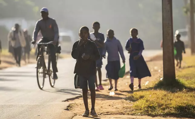 People walk in the street in Lilongwe, Malawi, Wednesday, June 12, 2024, following the death of Malawi's Vice President, Saulos Chilima, in a plane crash Monday. The Malawi government says that Chilima will be honored with a state funeral after he was killed along with eight other people in a plane crash. (AP Photo/Thoko Chikondi)