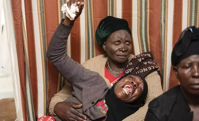 A mourner is comforted in Lilongwe, Malawi, Wednesday, June 12, 2024, following the death of Malawi's Vice President, Saulos Chilima, in a plane crash Monday. The Malawi government says that Chilima will be honored with a state funeral after he was killed along with eight other people in a plane crash. (AP Photo/Thoko Chikondi)