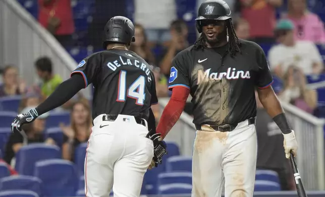 Miami Marlins' Josh Bell congratulates Bryan De La Cruz (14) after De La Cruz hit a solo home run during the sixth inning of a baseball game against the Seattle Mariners, Friday, June 21, 2024, in Miami. (AP Photo/Marta Lavandier)