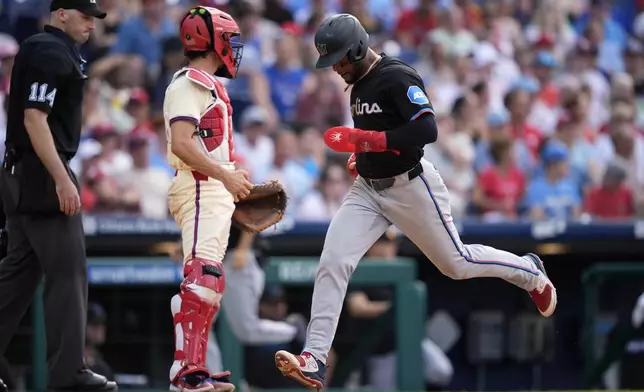 Miami Marlins' Otto Lopez, right, scores past Philadelphia Phillies catcher Garrett Stubbs on a double by Nick Fortes during the seventh inning of a baseball game, Saturday, June 29, 2024, in Philadelphia. (AP Photo/Matt Slocum)