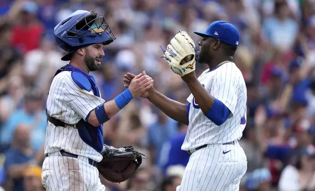 Chicago Cubs catcher Tomás Nido, left, and relief pitcher Héctor Neris celebrate after their win over the New York Mets in a baseball game Saturday, June 22, 2024, in Chicago. (AP Photo/Charles Rex Arbogast)