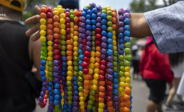 A vendor hawks rainbow-colored necklaces during the annual Gay Pride parade marking the culmination of LGBTQ+ Pride month, in Mexico City, Saturday, June 29, 2024. (AP Photo/Jon Orbach)