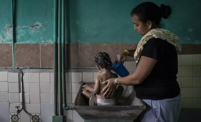 Rosana Mercado, a Venezuelan migrant, bathes her daughter inside the Peace Oasis of the Holy Spirit Amparito shelter, in Villahermosa, Mexico, Friday, June 7, 2024. After the head of Mexico's immigration agency ordered a halt to deportations in December, migrants have been left in limbo as authorities round up migrants across the country and dump them in the southern Mexican cities of Villahermosa and Tapachula. (AP Photo/Felix Marquez)