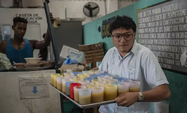 Josue Martinez serves juice to migrants during lunch at the Peace Oasis of the Holy Spirit Amparito shelter in Villahermosa, Mexico, Friday, June 7, 2024. "Mexico is the wall," said Martínez, a psychologist at the only shelter in Villahermosa. "(The migrants) are trapped in the south," referring to Mexican authorities' tactic of wearing migrants out until they can no longer continue. (AP Photo/Felix Marquez)