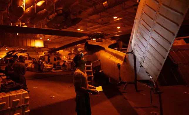 A crew member checks a helicopter in the hangar bay of the USS Dwight D. Eisenhower in the Red Sea on Tuesday, June 11, 2024.(AP Photo/Bernat Armangue)