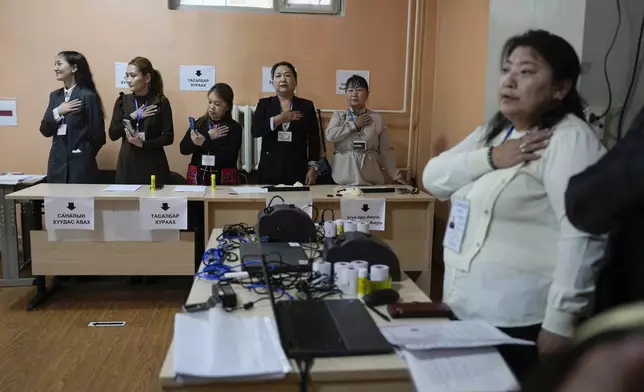 Electoral workers sing the national anthem before polling starts at a polling station in Ulaanbaatar, Mongolia, Friday, June 28, 2024. Voters in Mongolia are electing a new parliament on Friday in their landlocked democracy that is squeezed between China and Russia, two much larger authoritarian states. (AP Photo/Ng Han Guan)