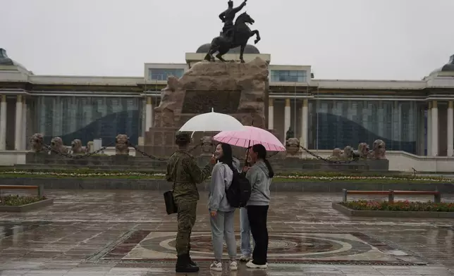 Young Mongolians chat under umbrellas as it rains on Sukhbaatar Square in Ulaanbaatar, Mongolia on Thursday, June 27, 2024. Mongolia, where parliamentary elections are being held Friday, is a sparsely populated and landlocked Asian nation known for its bitter winter cold and independent spirit. (AP Photo/Ng Han Guan)