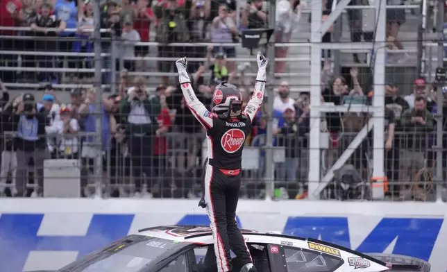 Christopher Bell raises his arms as he faces the crowd after winning the NASCAR Cup Series race at New Hampshire Motor Speedway, Sunday, June 23, 2024, in Loudon, N.H. (AP Photo/Steven Senne)