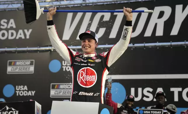 Christopher Bell hold up a broom after winning the NASCAR Cup Series race at New Hampshire Motor Speedway, Sunday, June 23, 2024, in Loudon, N.H. (AP Photo/Steven Senne)