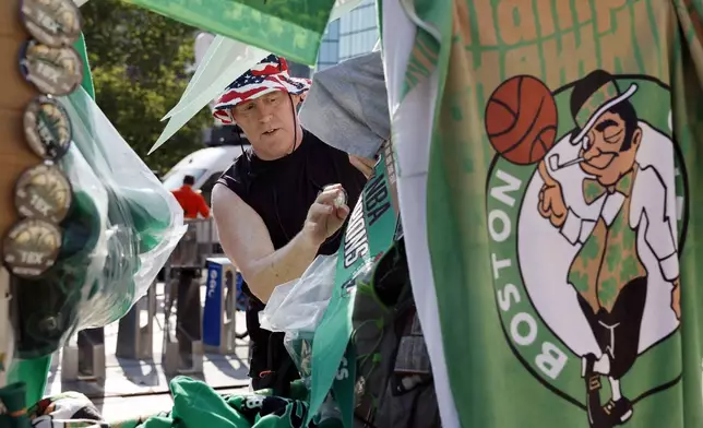 Rusty Dillenger, of Quincy, Mass., sells souvenirs in Copley Square before the Boston Celtics NBA basketball championship celebration parade Friday, June 21, 2024, in Boston. (AP Photo/Michael Dwyer)