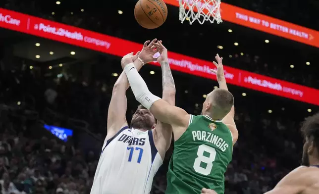 Dallas Mavericks guard Luka Doncic (77) shoots at the basket as Boston Celtics center Kristaps Porzingis (8) defends during the second half of Game 5 of the NBA basketball finals, Monday, June 17, 2024, in Boston. (AP Photo/Charles Krupa)