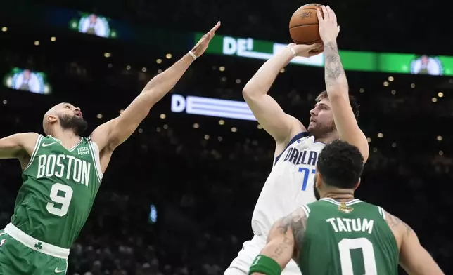 Dallas Mavericks guard Luka Doncic,top right, looks to shoot at the basket as Boston Celtics guard Derrick White (9) and forward Jayson Tatum (0) defend during the second half of Game 5 of the NBA basketball finals, Monday, June 17, 2024, in Boston. (AP Photo/Charles Krupa)