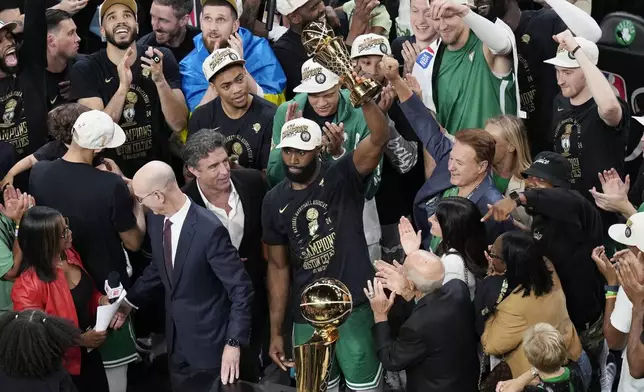 Boston Celtics' Jaylen Brown, center, raises the MVP trophy after defeating the Dallas Mavericks in Game 5 of the NBA basketball finals, Monday, June 17, 2024, in Boston. (AP Photo/Michael Dwyer)