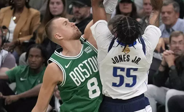 Boston Celtics center Kristaps Porzingis (8) defends as Dallas Mavericks forward Derrick Jones Jr. (55) looks to shoot at the basket during the second half of Game 5 of the NBA basketball finals, Monday, June 17, 2024, in Boston. (AP Photo/Charles Krupa)