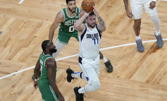 Dallas Mavericks guard Luka Doncic (77)goes up to shoot at the basket in front of Boston Celtics guard Jaylen Brown, left, and forward Jayson Tatum (0) during the first half of Game 5 of the NBA basketball finals, Monday, June 17, 2024, in Boston. (AP Photo/Michael Dwyer)