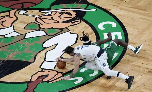 Boston Celtics' Jrue Holiday, right, and Dallas Mavericks' Luka Doncic (77) battle for the ball during the first half of Game 5 of the NBA basketball finals, Monday, June 17, 2024, in Boston. (AP Photo/Michael Dwyer)
