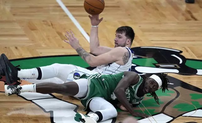 Dallas Mavericks guard Luka Doncic, top, and Boston Celtics guard Jrue Holiday, bottom, land on the parquet as they vie for the ball during the first half of Game 5 of the NBA basketball finals, Monday, June 17, 2024, in Boston. (AP Photo/Charles Krupa)