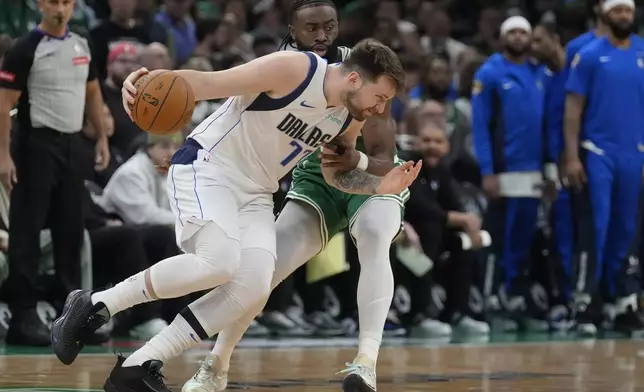 Dallas Mavericks guard Luka Doncic, front, drives with the ball as Boston Celtics guard Jaylen Brown, back, defends during the first half of Game 5 of the NBA basketball finals, Monday, June 17, 2024, in Boston. (AP Photo/Charles Krupa)