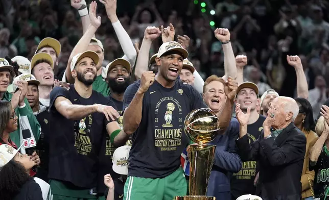 Boston Celtics center Al Horford, center, and forward Jayson Tatum, front center left, celebrate with teammates near the Larry O'Brien Championship Trophy after winning the NBA championship with a Game 5 victory over the Dallas Mavericks on Monday, June 17, 2024, in Boston. (AP Photo/Charles Krupa)
