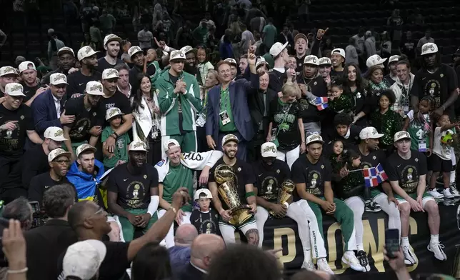 Boston Celtics forward Jayson Tatum, center, holds the Larry O'Brien Championship Trophy as he celebrates with the team after they won the NBA basketball championship with a Game 5 victory over the Dallas Mavericks, Monday, June 17, 2024, in Boston. (AP Photo/Charles Krupa)