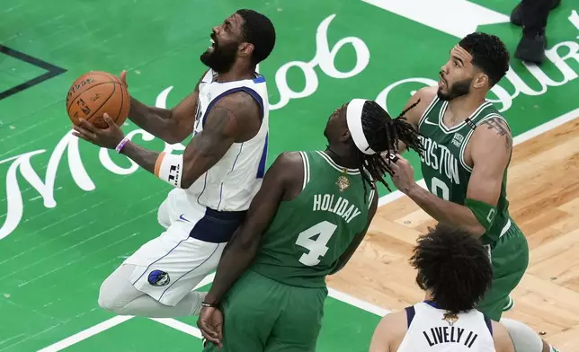 Dallas Mavericks' Kyrie Irving, left, shoots against Boston Celtics' Jrue Holiday (4) and Jayson Tatum (0) during the second half of Game 5 of the NBA basketball finals, Monday, June 17, 2024, in Boston. (AP Photo/Michael Dwyer)