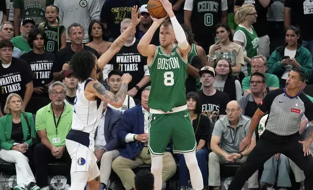 Boston Celtics center Kristaps Porzingis (8) looks to shoot at the basket as Dallas Mavericks center Dereck Lively II, left, defends during the second half of Game 5 of the NBA basketball finals, Monday, June 17, 2024, in Boston. (AP Photo/Charles Krupa)