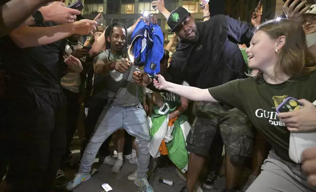 Boston Celtics fans attempt to light a Dallas Mavericks jersey on fire outside the TD Garden following the Celtics victory over the Mavericks in Game 5 of the NBA basketball finals in Boston, Monday, June 17, 2024. (AP Photo/Josh Reynolds)