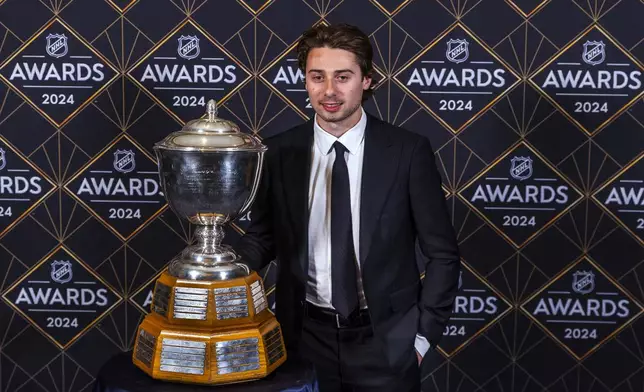 Vancouver Canucks defenseman Quinn Hughes stands with the James Norris Memorial Trophy at hockey's NHL Awards, Thursday, June 27, 2024, in Las Vegas. (AP Photo/L.E. Baskow)