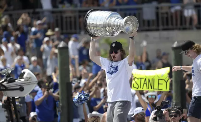 FILE - Tampa Bay Lightning defenseman Mikhail Sergachev hoists the Stanley Cup while riding on a boat with goaltender Andrei Vasilevskiy, right, during the NHL hockey Stanley Cup champions' Boat Parade, Monday, July 12, 2021, in Tampa, Fla. The Utah Hockey Club made a big splash at its first draft, acquiring two-time Stanley Cup-winning defenseman Mikhail Sergachev from the Tampa Bay Lightning. (AP Photo/Phelan M. Ebenhack, File)