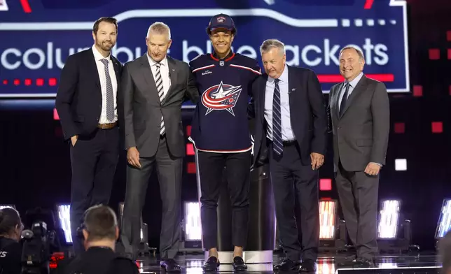 Cayden Lindstrom, center, poses after being selected by the Columbus Blue Jackets during the first round of the NHL hockey draft Friday, June 28, 2024, in Las Vegas. (AP Photo/Steve Marcus)