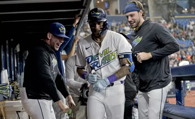 Tampa Bay Rays' Ben Rortvedt, left, and Josh Lowe, right, congratulate Jose Siri, center, in the dugout after his solo home run off Washington Nationals starter Mitchell Parker during the second inning of a baseball game Friday, June 28, 2024, in St. Petersburg, Fla. (AP Photo/Steve Nesius)