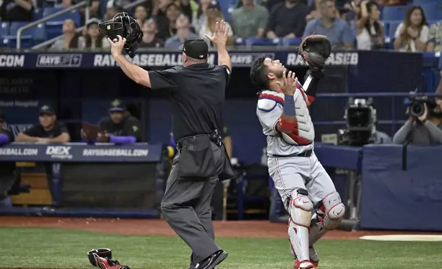 Uumpire Dan Bellino, left, signals a foul ball as Washington Nationals catcher Keibert Ruiz waits for a pop fly that got stuck in the catwalk during the first inning of a baseball game Saturday, June 29, 2024, in St. Petersburg, Fla. (AP Photo/Steve Nesius)
