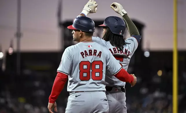 Washington Nationals first base coach Gerardo Parra and CJ Abrams celebrate Abrams' RBI single against the Colorado Rockies durinng the seventh inning of a baseball game Saturday, June 22, 2024, in Denver. (AP Photo/Geneva Heffernan)