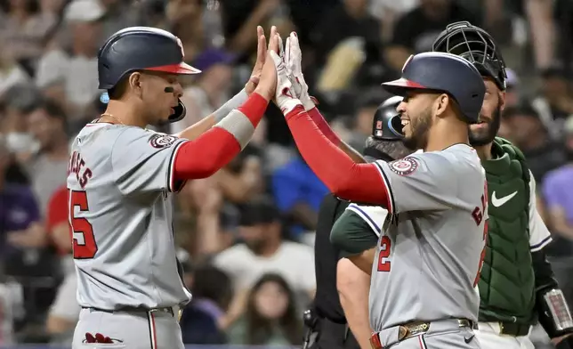 Washington Nationals first baseman Joey Meneses, left, and Luis García Jr. celebrate a two-run home run by García against the Colorado Rockies during the eighth inning of a baseball game Saturday, June 22, 2024, in Denver. (AP Photo/Geneva Heffernan)