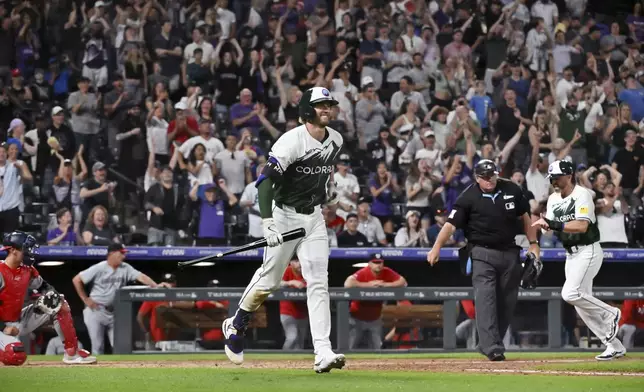 Colorado Rockies' Ryan McMahon heads to first on a bases-loaded walk, driving in Jake Cave, right rear, with the winning run against the Washington Nationals in a baseball game Saturday, June 22, 2024, in Denver. (AP Photo/Geneva Heffernan)
