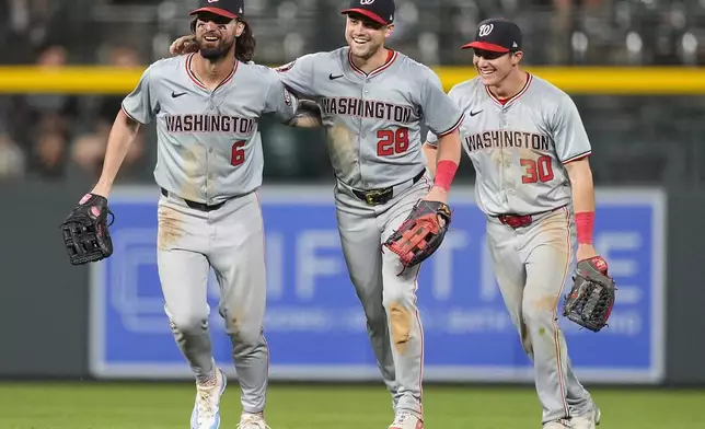 Washington Nationals left fielder Jesse Winker, right fielder Lane Thomas and center fielder Jacob Young, from left, smile after the team's win in a baseball game against the Colorado Rockies on Friday, June 21, 2024, in Denver. (AP Photo/David Zalubowski)