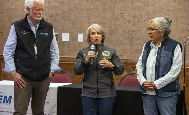 New Mexico Gov. Michelle Lujan Grisham, flanked by the mayor of Ruidoso Lynn Crawford, left, and the Mescalero Apache Tribe president Thora Walsh Padilla speaks during a media briefing in the mountain village of Ruidoso, N.M., Saturday, June 22, 2024. Recent rains and cooler weather are helping firefighters gain ground on two wildfires in southern New Mexico. (AP Photo/Andres Leighton)