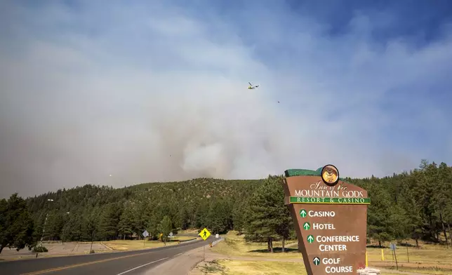 A helicopter flies over smoke from a wildfire seen from the Inn of the Mountain Gods Resort in Ruidoso, N.M., Tuesday, June 18, 2024. Thousands of residents fled their homes as a wildfire swept into the mountain village of Ruidoso in southern New Mexico. (AP Photo/Andres Leighton)
