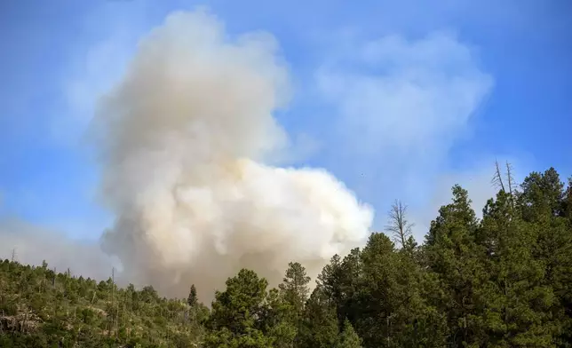 Smoke from a wildfire rises over the mountains of Ruidoso, N.M., Tuesday, June 18, 2024. Thousands of residents fled their homes as a wildfire swept into the mountain village of Ruidoso in southern New Mexico. (AP Photo/Andres Leighton)