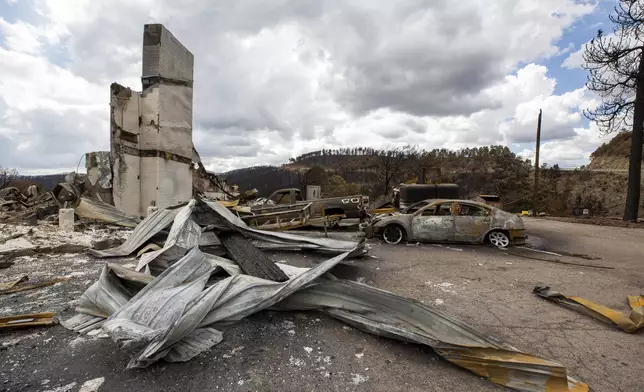Charred vehicles and debris cover the parking lot of the Swiss Chalet Hotel after it was destroyed by the South Fork Fire in the mountain village of Ruidoso, N.M., Saturday, June 22, 2024. (AP Photo/Andres Leighton)