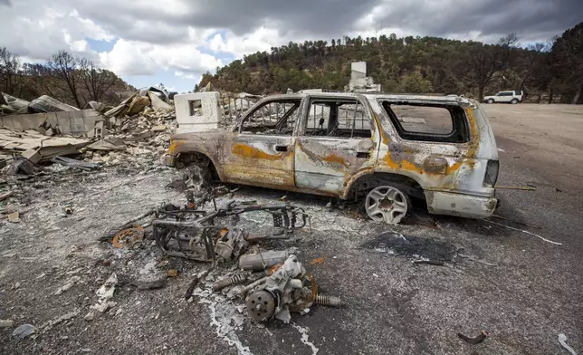 A charred car sits among the remains of the Swiss Chalet Hotel after it was destroyed by the South Fork Fire in the mountain village of Ruidoso, N.M., Saturday, June 22, 2024. (AP Photo/Andres Leighton)