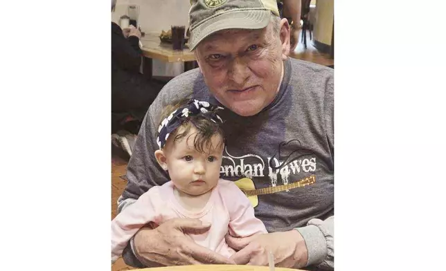 This undated image provided by Hilary Mallak shows her father, Patrick Pearson, holding his granddaughter Harlynn Mallak. Pearson was found dead outside of the Swiss Chalet Inn in Ruidoso, New Mexico, where he lived after smoke and flames from a pair of fast-moving wildfires moved into the community. Thousands of residents were forced to evacuate and authorities have estimated 1,400 structures have been damaged or destroyed. (Hilary Mallak via AP)