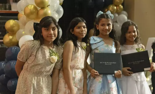 Sophia Prado, left, takes a picture with her classmates after a graduation ceremony at Trevor Day School, Friday, June 21, 2024, in New York. Thousands of migrant families in New York City are facing a summer of uncertainty for their school-aged children with a citywide limit of 60 days in a shelter before needing to reapply or find their own. (AP Photo/Jeenah Moon)