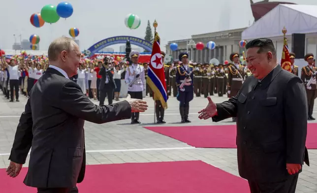 Russian President Vladimir Putin, left, and North Korea's leader Kim Jong Un, foreground right, shake hands during the official welcome ceremony in the Kim Il Sung Square in Pyongyang, North Korea, on Wednesday, June 19, 2024. (Gavriil Grigorov, Sputnik, Kremlin Pool Photo via AP)