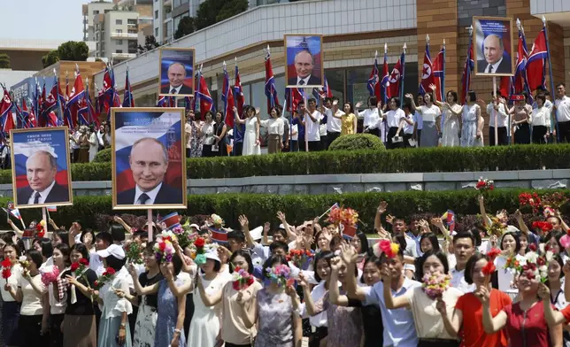 People, holding portraits of Russian President Vladimir Putin, greet and applaud as a motorcade with Russian President Vladimir Putin and North Korea's leader Kim Jong Un move past in a street in Pyongyang, North Korea, Wednesday, June 19, 2024. (Gavriil Grigorov, Sputnik, Kremlin Pool Photo via AP)
