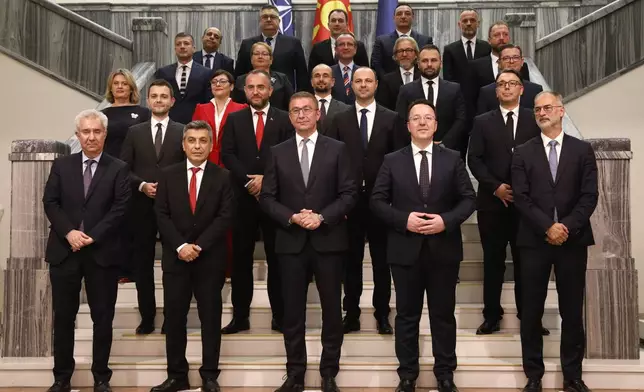 Hristijan Mickoski, center foreground, new North Macedonia's prime minister, and the members of his cabinet stand together for a photo after the parliament elected the new government, in the parliament building in Skopje, North Macedonia, late Sunday, June 23, 2024. North Macedonia's parliament has approved a new conservative government late on Sunday proposed by a center-right party that won May's national elections. (AP Photo/Boris Grdanoski)