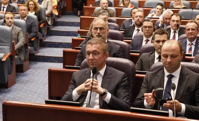 Hristijan Mickoski, center, the new North Macedonia's prime minister and the members of his cabinet sit together after lawmakers voted for the new government, during a session of parliament in Skopje, North Macedonia, late Sunday, June 23, 2024. North Macedonia's parliament has approved a new conservative government late on Sunday proposed by a center-right party that won May's national elections. (AP Photo/Boris Grdanoski)