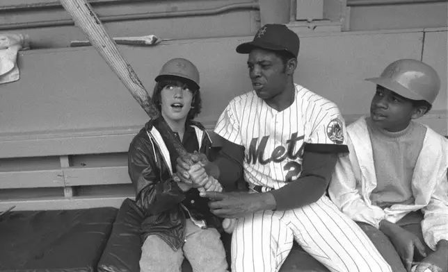 FILE - New York Mets' Willie Mays, center, shows John F. Kennedy Jr., left, the proper grip on the bat June 3, 1972, in the dugout at New York's Shea Stadium. At right is Eric Von Huguley, a friend who joined young John in a visit to the Mets' dugout before the game against the Atlanta Braves. Mays, the electrifying “Say Hey Kid” whose singular combination of talent, drive and exuberance made him one of baseball’s greatest and most beloved players, has died. He was 93. Mays' family and the San Francisco Giants jointly announced Tuesday night, June 18, 2024, he had “passed away peacefully” Tuesday afternoon surrounded by loved ones. (AP Photo, File)